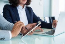 Two people discussing with laptop and tablet in hand