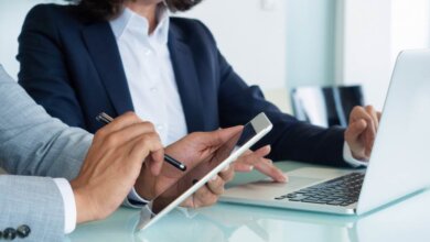 Two people discussing with laptop and tablet in hand
