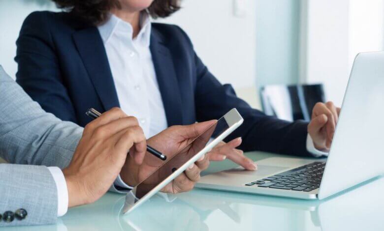 Two people discussing with laptop and tablet in hand