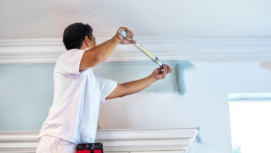 Painter using an extension pole to paint a ceiling.