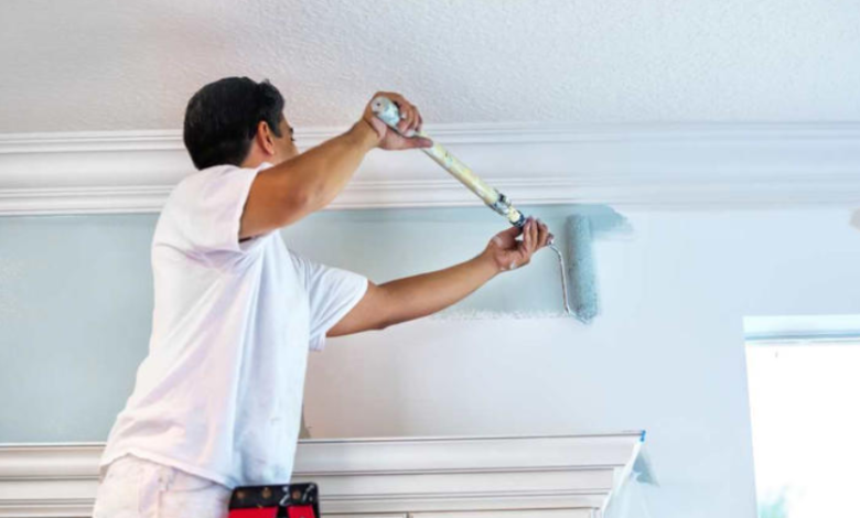 Painter using an extension pole to paint a ceiling.