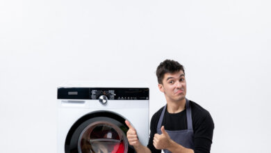Man in apron giving thumbs up near washing machine. Same-day repair in Dubai.