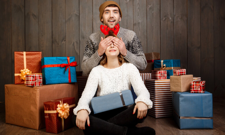 A man and woman sit on a wooden floor surrounded by colorful presents, celebrating meaningful gift ideas for special occasions.