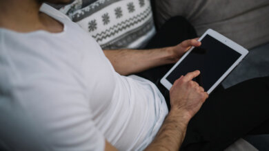 A man on a couch, engaged with a tablet, demonstrating the We2usat K3 Pro and vSeeBox V3 Plus in 2025.