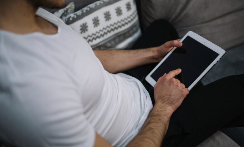 A man on a couch, engaged with a tablet, demonstrating the We2usat K3 Pro and vSeeBox V3 Plus in 2025.