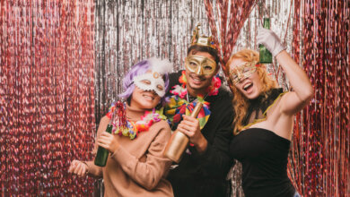 Three people in colorful costumes smiling and posing together for a photo at a birthday party photo booth in Texas.