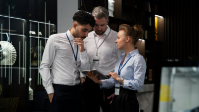 Three people gathered around a computer, analyzing a guide related to event security and on-site protection in AL.