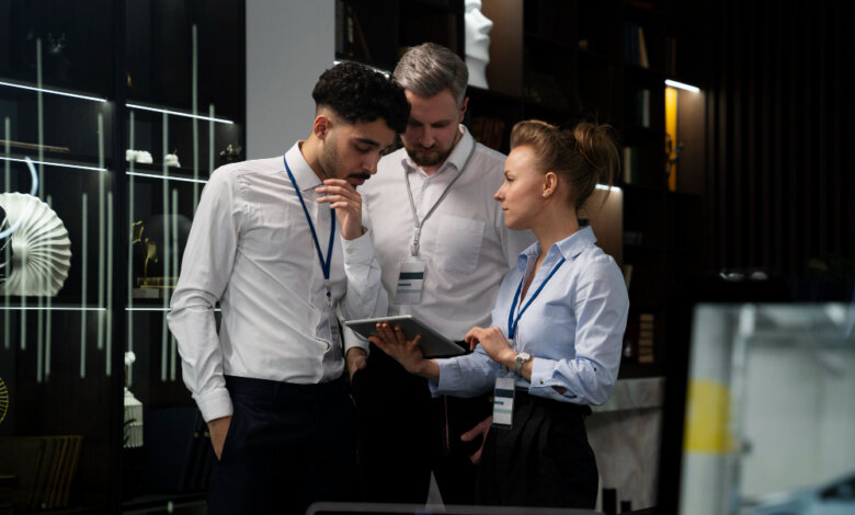 Three people gathered around a computer, analyzing a guide related to event security and on-site protection in AL.