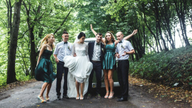 A group of people smiling and posing beside a decorated wedding car, representing Group Travel Experts for weddings in NC.
