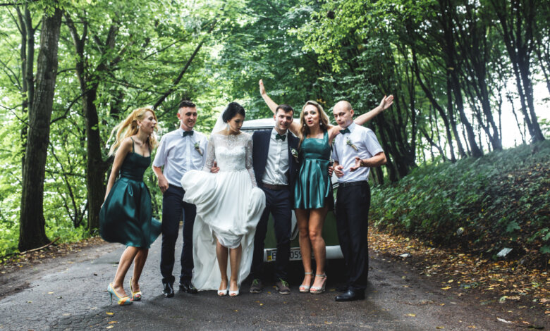 A group of people smiling and posing beside a decorated wedding car, representing Group Travel Experts for weddings in NC.