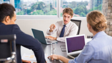 Business team of three at a table with laptops, working together on staffing and placement support for various businesses.