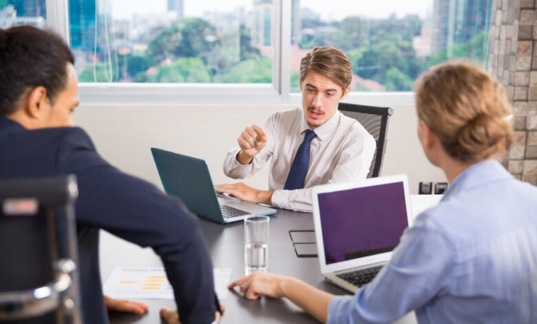 Business team of three at a table with laptops, working together on staffing and placement support for various businesses.
