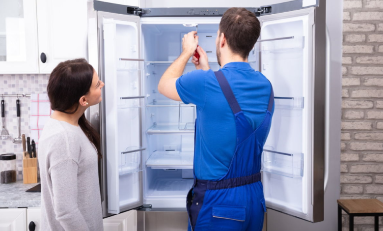 Refrigerator repair technician fixing appliance for homeowner