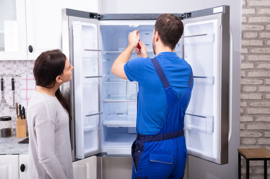Refrigerator repair technician fixing appliance for homeowner