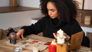 A woman playing cards at a table, navigating life through tarot and spiritual guidance in California.
