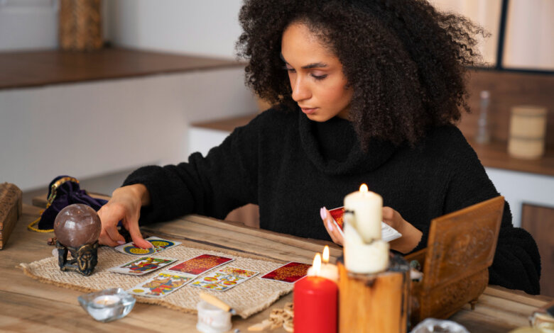A woman playing cards at a table, navigating life through tarot and spiritual guidance in California.