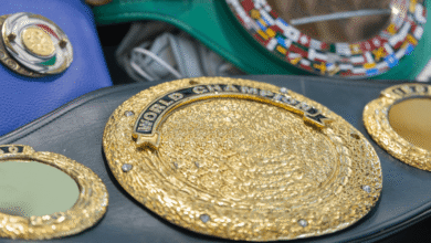 Close-up of a boxing belt featuring intricate gold detailing and a vibrant blue background.