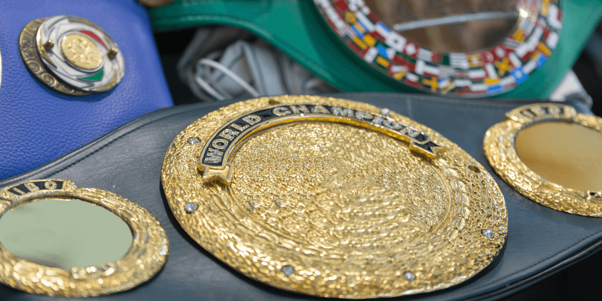 Close-up of a boxing belt featuring intricate gold detailing and a vibrant blue background.