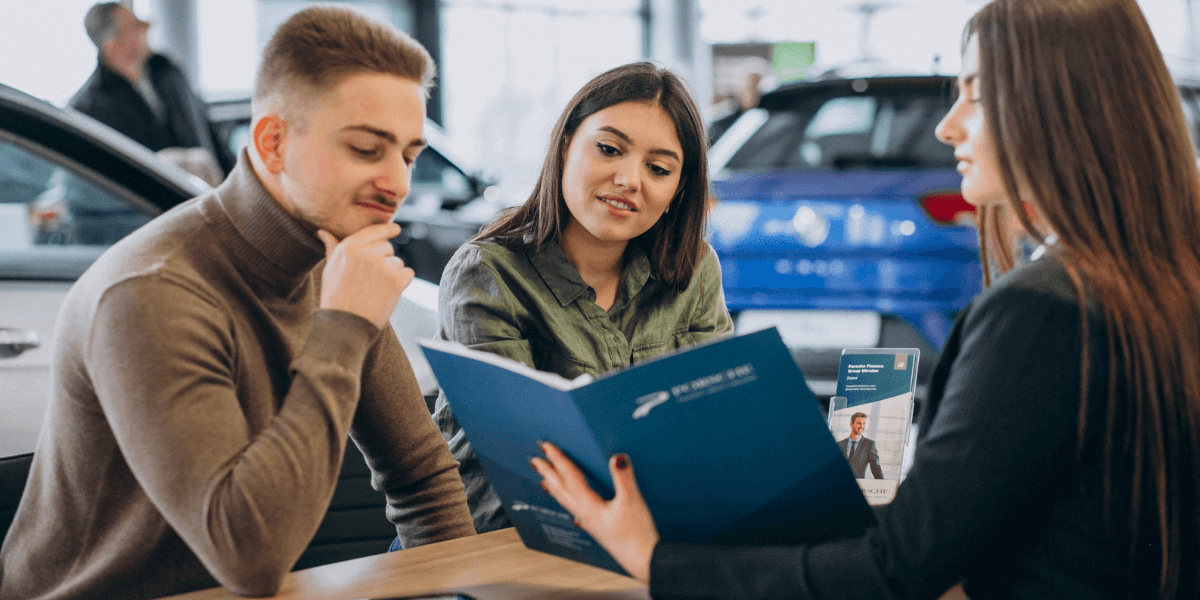 Two individuals examining a car inside a dealership, discussing its features and options.