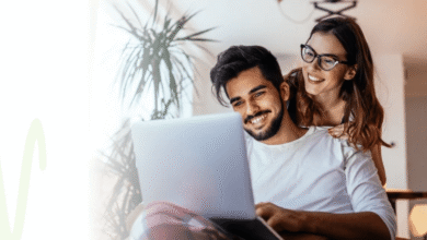 A man and woman relax on a couch, sharing a moment as they view a laptop together